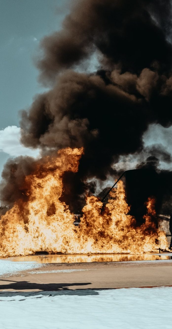 Fire engulfing a landscape with thick black smoke rising into the sky.