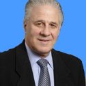 Smiling man in a suit against a blue background.